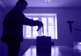 Uomo inserisce una scheda nell urna di un locale elettorale.