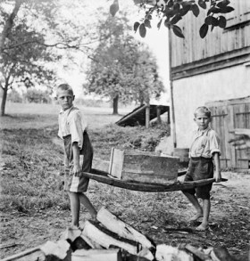 Immagine in biaco e nero di due bambini che trasportano un trogolo