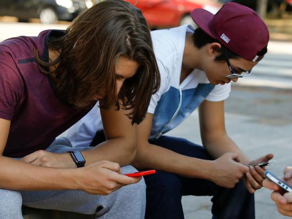 tre giovani seduti intenti ad utilizzare i loro smartphone