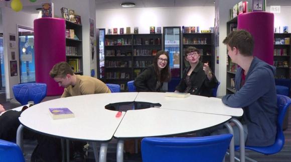 Giovani britannici discutono seduti a un tavolo