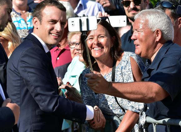 Il presidente francese Emmanuel Macron in mezzo alla folla si presta ai selfie.