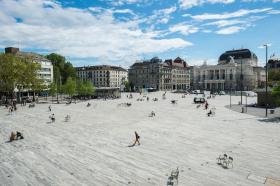 Platz vor dem Opernhaus Zürich, wo Leute in der Sonne flanieren und sitzen.