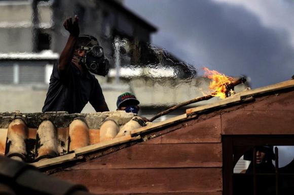 Un immagine degli scontri tra manifestanti oppositori e polizia durante la prima giornata di sciopero generale in Venezuela.