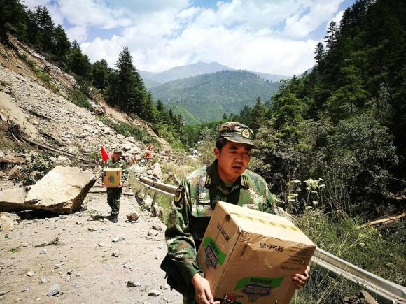 Un soccorritore porta a piedi, verso le zone colpite dal terremoto in Cina, beni di prima necessità.