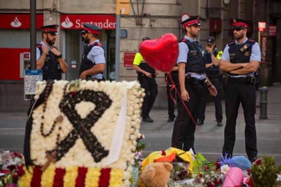 Poliziotti spagnoli dietro a mazzi di fiori deposti sulla Rambla dopo l attentato