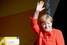 Frau Merkel in roter Kleidung winkt