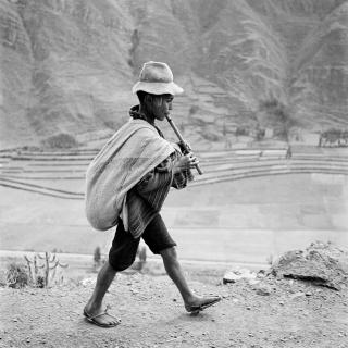 bambino suona un flauto mentre cammina sulla strada per Cuzco