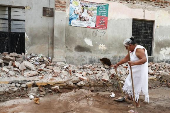 Una mujer intenta limpiar los escombros tras el terremoto.