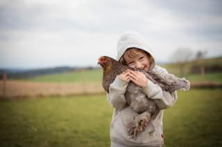 Bub umarmt ein Huhn und lächelt