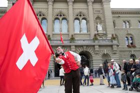 Uno sbandieratore fa volteggiare la bandiera svizzera davanti al Palazzo federale.