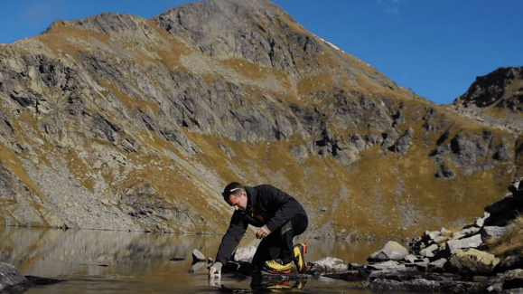 Ricercatore mentre preleva un campione d acqua da un lago di montagna