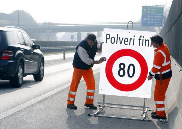 Due operai posano il cartello temporaneo Polveri fini, limite a 80 km/h in un immagine d archivio.