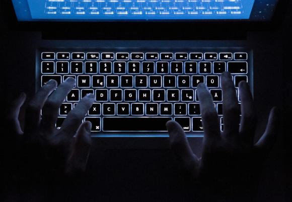 In un immagine puramente illustrativa, un uomo digita su una tastiera di computer in penombra.