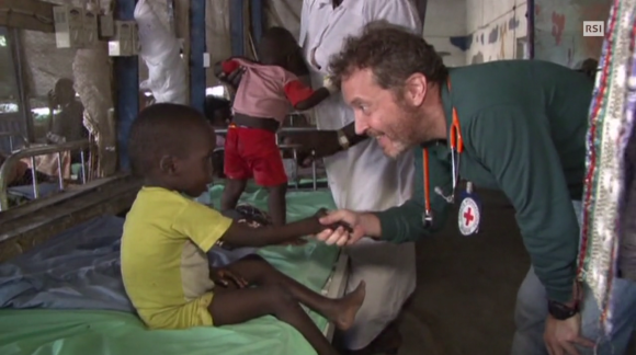 Un medico stringe la mano a un bambino in un centro della Croce Rossa in Africa