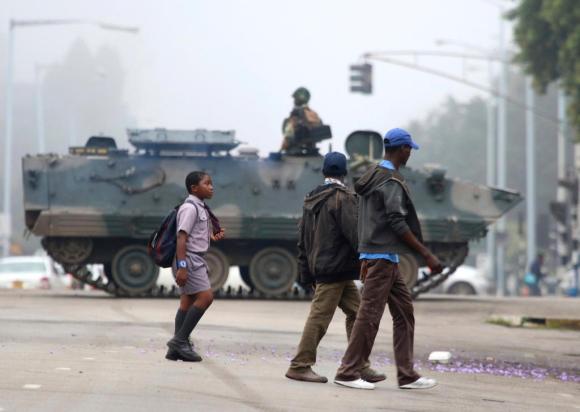 Ragazzini di Harare, capitale dello Zimbabwe, vanno a scuola; sullo sfondo un carro armato