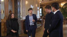 Una giovane donna e tre giovani uomini in piedi in semicerchio nella Sala dei passi perduti del Palazzo federale discutono