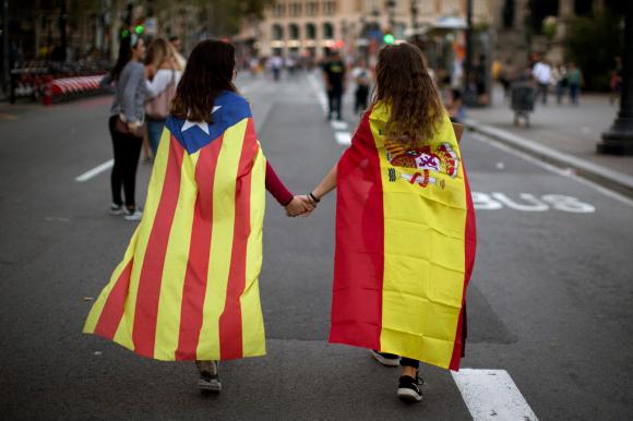 Due ragazzine (una con la bandiera spagnola, l altra catalana sulle spalle) di tengono per mano.