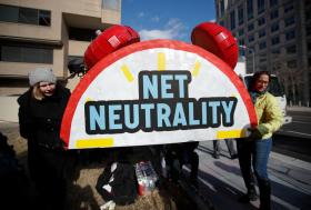 due persone tengono un cartellone su cui è scritto neutralità della rete
