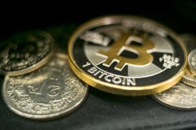1 bitcoin in mezzo ad alcune monete da 2 franchi.