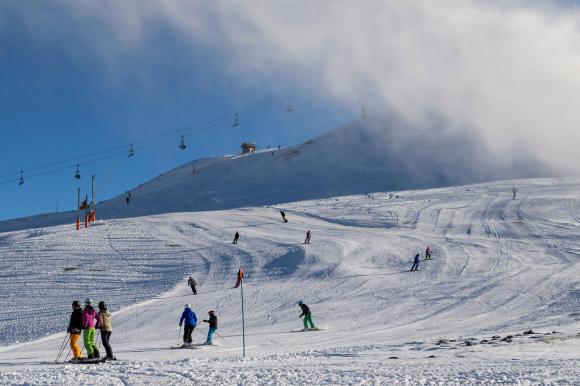 People skiing on wide slopes, with a chairlift in the background