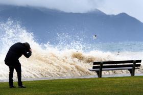 Un uomo si copre il capo all infrangersi di un onda sulle rive del Lago Lemano.
