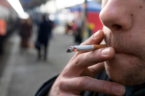 uomo fuma una sigaretta su un marciapiede di una stazione
