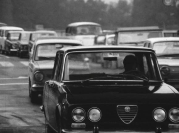 Immagine in bianco e nero (anni Sessanta) di auto incolonnate alla frontiera.