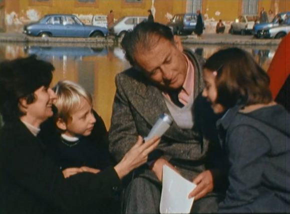 Gianni Rodari intervistato da una ragazzina. Nella foto anche un piccolo spettatore e una giornalista adulta.