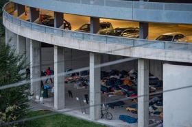 Immagine dell autosilo val Mulini a Como. Al piano superiore, vetture. Sotto, sacchi a pelo e coperte dei migranti.