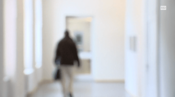 Immagine sfocata di una persona sola che cammina per un corridoio.