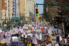 Immagine del corteo a New York, con migliaia di persone che sfilano reggendo cartelli su Central Park West.
