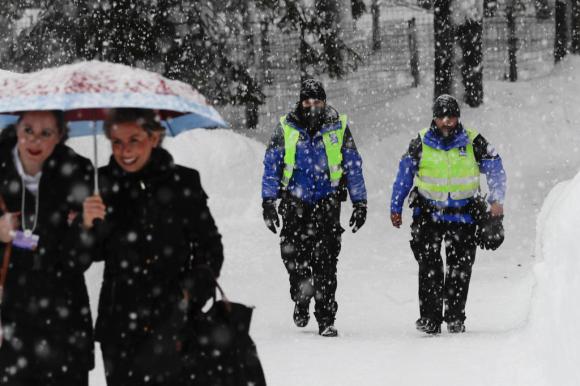 due donne e due poliziotti a piedi sotto la neve a Davos