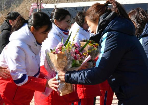 Giocatrici nordcoreane di hockey su ghiaccio ricevono un mazzo di fiori da compagne sudcoreane.