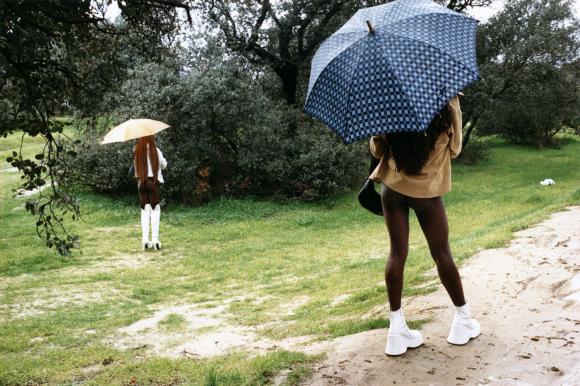 due prostitute nigeriane con gli ombrelli aperti, viste di spalle.