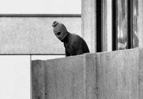 Un uomo con il volto coperto da un passamontagna su un balcone.
