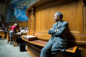 Tim Guldimann seduto sotto una tribuna nella sala del Consiglio nazionale segue i dibattiti in aula.