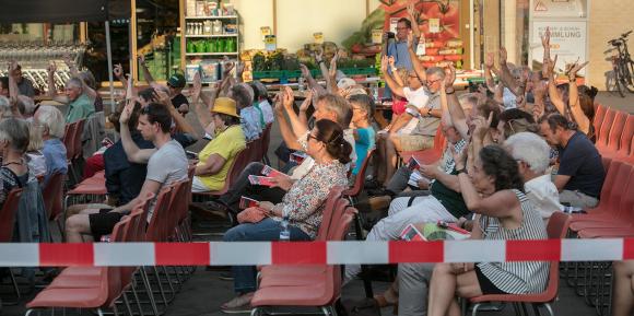Bürger stimmen an einer Freiluft-Gemeindeversammlung mit Handerheben ab