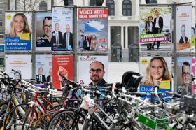 Biciclette parcheggiate davanti a una serie di cartelloni di campagna elettorale.