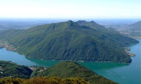 Veduta aerea e piena del Monte San Giorgio, con il lago circostante; si intravede sul fondo la Pianura Padana