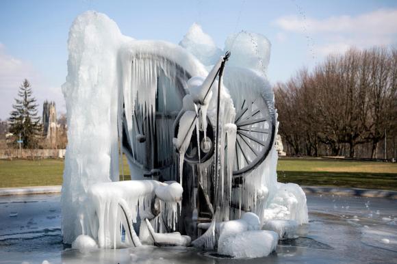 Immagine della scultura Joe Siffert di Jean Tinguely a Friburgo completamente ghiacciata, sullo sfondo il parco