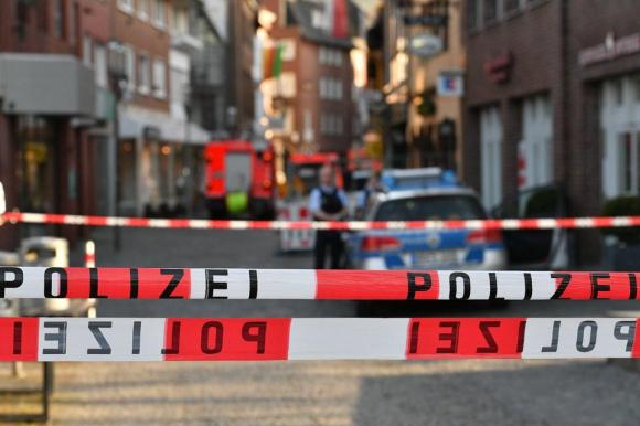 Nastro con la scritta Polizei in primo piano, a sbarrare un centro storico con auto della polizia sul fondo