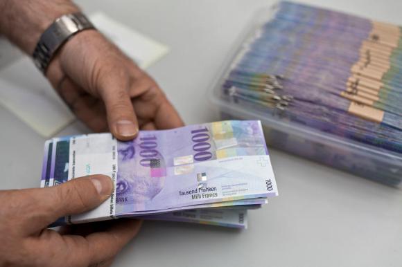 Due mani stringono un mazzo di banconote da mille franchi.