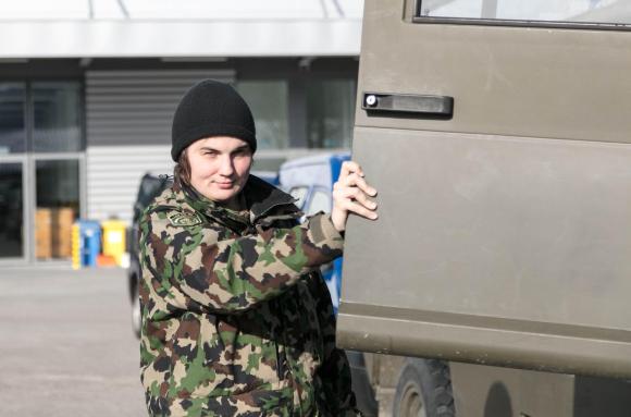 una soldatessa aopre la protiera di un veicolo militare