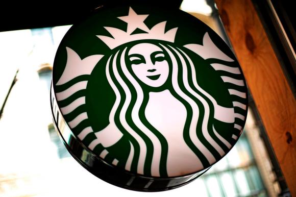 Primo piano di insegna luminosa con il logo di Starbucks nella vetrina di un punto vendita