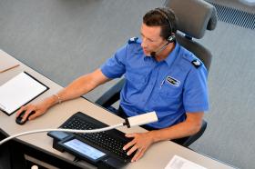 Ein Polizist mit Headset am Computer