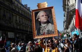 corteo di manifestanti antimacron, con un dimostrante che tiene un manifesto con la fotografia di Macron in veste Luigi XVI