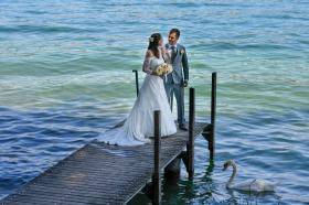 Una coppia di sposi sull imbarcadero e un cigno che galleggia sul lago sottostante.