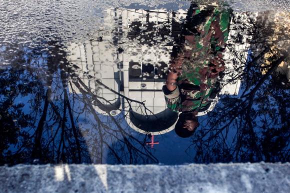 Immagine di un soldato davanti a una chiesa cristiana specchiata in una pozza d acqua.
