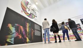 Gruppetto di persone di fronte a una parete con gigantografia di Hendrix e testo introduttivo alla mostra