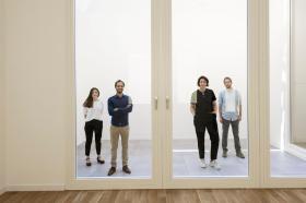 Quattro persone in piedi dietro una porta a vetri gigantesca